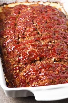 meatloaf in a white casserole dish with sauce on top