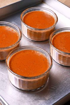 four small glass bowls filled with sauce on top of a metal tray