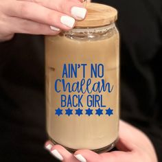 a woman holding a jar of coffee with blue writing on it that says,'ain't no chafeean back girl '