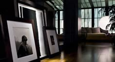 a living room filled with furniture and framed pictures on the floor next to a plant