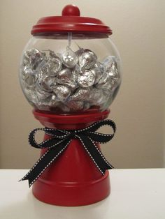 a red gummy machine filled with lots of silver foil wrapped in black ribbon and bow