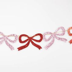 a red and pink ribbon is hanging from a string on a white background with the word love spelled in it