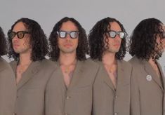 a group of men with long hair and glasses on their faces are standing in front of a white wall