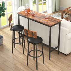 three stools and a bar table in a room with hardwood floors, windows, and white couches