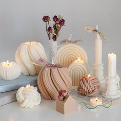 candles, vases and other decorative items are arranged on a white table top with books