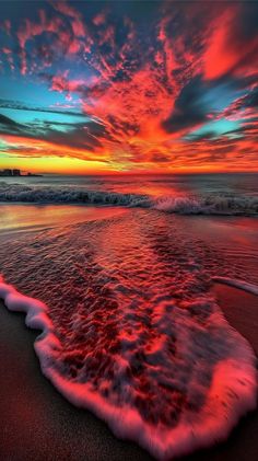 the sun is setting at the beach with waves coming in to shore and red clouds