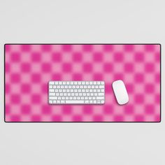 a computer keyboard and mouse on a pink checkerboard surface with a white mouse pad