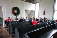 people sitting in pews at a church with wreath hanging on the wall behind them