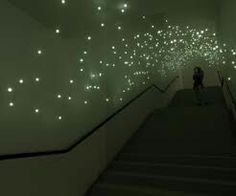 a person is walking down some stairs with lights on the walls and ceiling above them