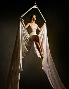 a woman is hanging upside down in the air with her legs spread out and holding on to an object