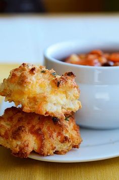 two fried food items on a plate with a bowl of soup in the back ground