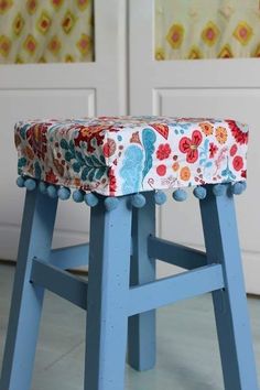 a blue stool with a flowered seat cover on it