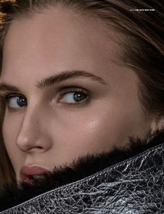 a woman with long hair and blue eyes is looking at the camera while wearing a fur collar