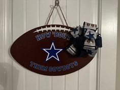 a football shaped sign hanging on the wall with a bow tied to it's side