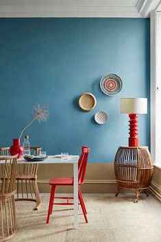 a dining room with blue walls and red chairs