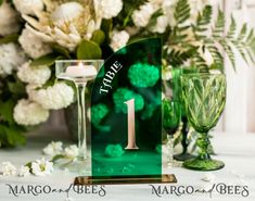 a table topped with two wine glasses next to a vase filled with flowers and greenery