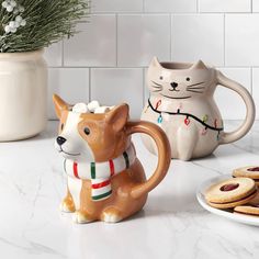 a ceramic cat mug and some cookies on a counter