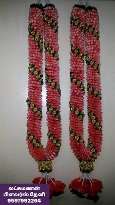 two red and gold garlands hanging from the ceiling with flowers on them, in front of