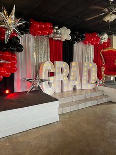 a stage set up for a graduation party with balloons and stars on the floor,