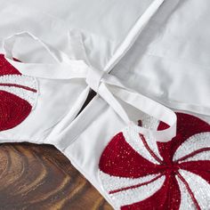 two red and white pillows on top of a wooden table next to a pillow case