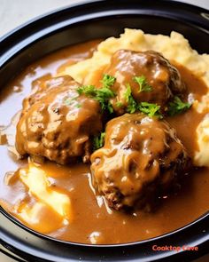 two meatballs covered in gravy on top of mashed potatoes