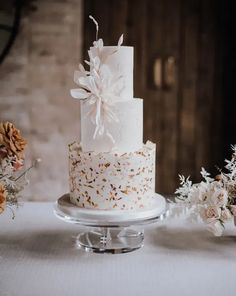 a three tiered wedding cake with white frosting and gold sprinkles