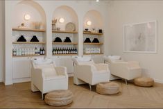 two white chairs sitting next to each other in front of shelves with bottles on them