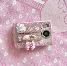 a pink camera sitting on top of a pink cloth covered tablecloth with an animal and bow decoration