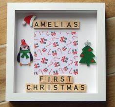 a wooden scrabble frame with christmas themed items in it and the words'first christmas '