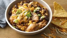 a white bowl filled with chicken and black bean chili next to tortilla chips