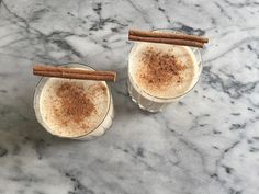 two glasses filled with cinnamon drink sitting on top of a marble counter