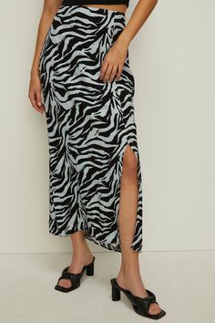 Striking zebra print midi skirt in viscose fabric Wrap-style design with thigh-high split for a sultry look Flattering high-waisted fit that cinches the waist Midi length hits below the knee for a versatile silhouette Lightweight and flowy fabric for effortless movement Embrace your wild side with this eye-catching zebra print midi skirt. The wrap-style design exudes a sultry vibe with its thigh-high split, while the high-waisted fit flatters your curves. Crafted from viscose, this skirt offers a lightweight and flowy feel, making it perfect for a night out on the town. Pair it with a sleek bodysuit and strappy heels for a glamorous evening look, or dress it down with a simple tee and trainers for a casual daytime ensemble. Conscious Clothing, Wrap Midi Skirt, Flowy Fabric, Oasis Fashion, Printed Midi Skirt, Simple Tees, Viscose Fabric, Strappy Heels, Thigh High