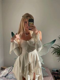 a woman in a white dress taking a selfie with her cell phone while standing on a bed