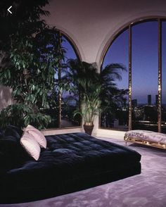 a living room filled with lots of furniture and large windows overlooking the city at night