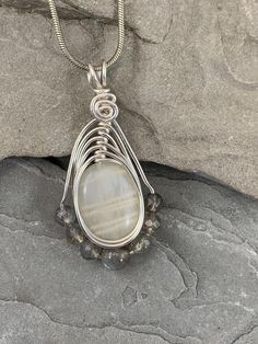 The tranquil beauty of this white moonstone and Labradorite  necklace is stunning. Moonstone has a soothing nurturing energy paired with Labradorite which holds the power of positivity, and it will negate all the negative energies around you.  The delicate glow of the moonstone is beautiful in its simplicity. I chose to enhance this beautiful stone with 7 genuine labradorite gemstones for added sparkle. Set in a Celtic inspired silver wire design to let the natural beauty of the gemstones shine. White Labradorite Necklace With Natural Stones, White Moonstone Crystal Necklace With Moon Charm, White Moon Phase Jewelry For Meditation, White Labradorite Bohemian Necklace, Bohemian White Labradorite Necklace, Handmade White Moon-shaped Necklace, Handmade White Moon Shaped Necklace, White Moonstone Moon Phase Necklace, White Moon-shaped Necklace With Natural Stones