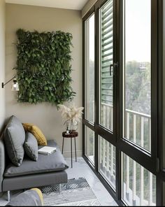 a living room with a couch, table and plants on the wall behind glass doors