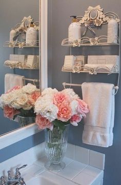 a bathroom sink with flowers in a vase on the counter and towels hanging above it