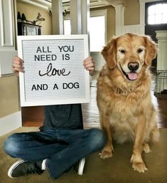 a person holding up a sign with a dog sitting next to them on the floor