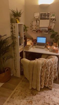 a laptop computer sitting on top of a white desk next to a potted plant