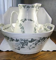 a white and green vase sitting on top of a wooden table next to a napkin