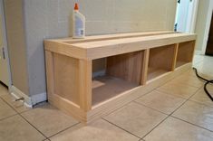 a wooden shelf sitting on top of a tiled floor next to a bottle of cleaner