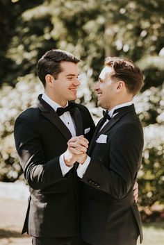 two men in tuxedos standing next to each other and looking at each other