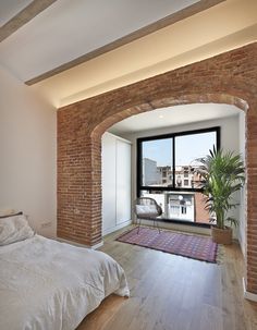 a bedroom with an arched brick wall and hardwood floors