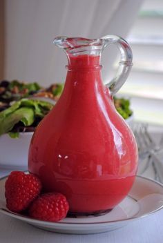 a glass pitcher filled with liquid sitting on top of a plate next to a salad