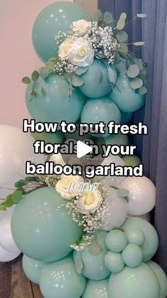 balloons are stacked on top of each other with flowers and greenery in the middle