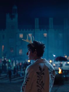 a man with a deer antlers headband standing in front of a building at night