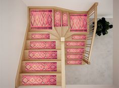 a stair case with pink and red designs on the wall next to a potted plant