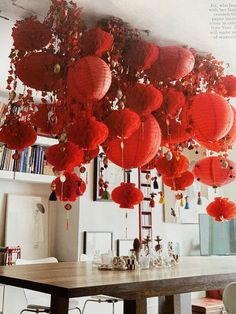 many red lanterns hanging from the ceiling above a table