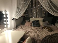 a dog laying on top of a bed next to a dresser and mirror with lights