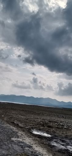 the sky is very cloudy and there are mountains in the distance on the far side